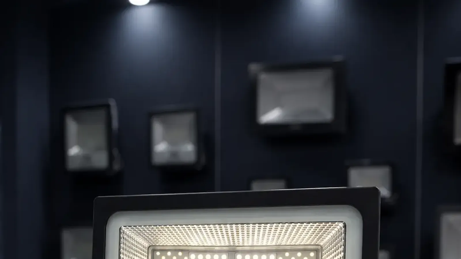An LED flood light lit, showing the die-cast housing and the array of LEDs behind the glass